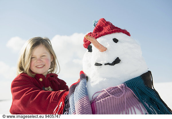 Portrait of girl standing with snowman  smiling