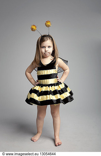 Portrait of girl wearing bee costume while standing against gray background