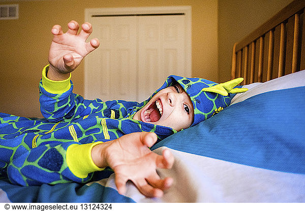 Portrait of girl wearing costume screaming while lying on bed at home during Halloween
