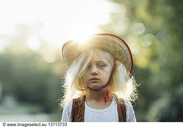 Portrait of girl wearing sun hat standing in park during sunny day