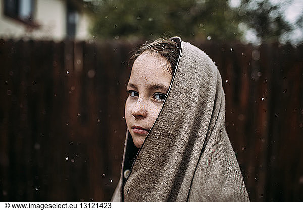 Portrait of girl wearing warm clothing at backyard during snowfall