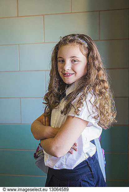 Portrait of girl with arms crossed standing in corridor