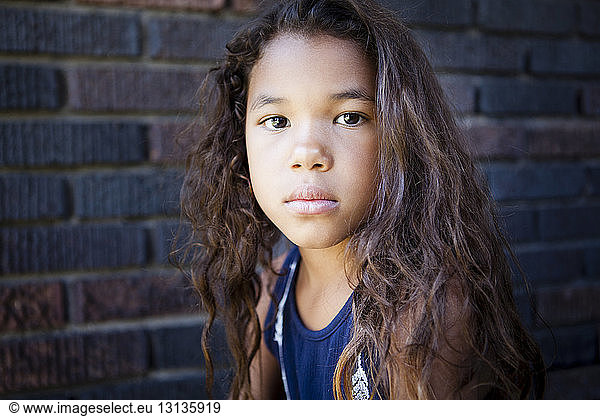 Portrait of girl with tousled hair against brick wall