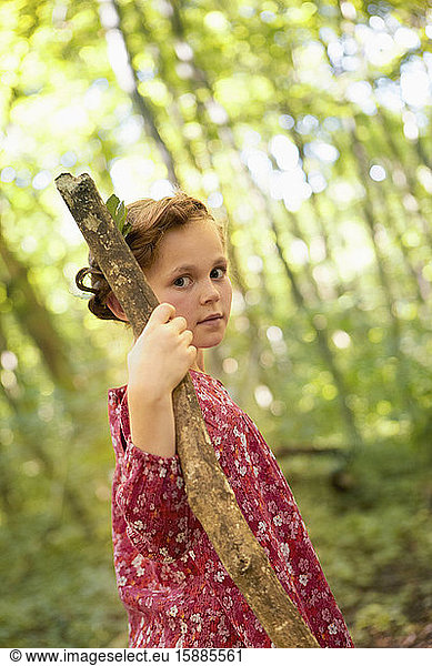 Portrait of girl with wood stick walking in forest