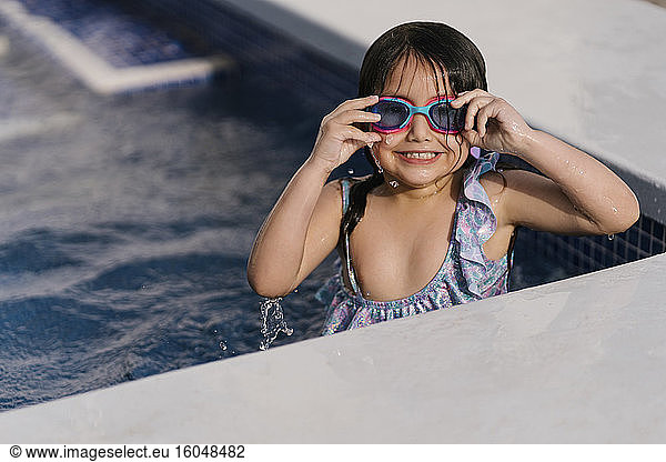 Portrait of grinning little girl with swimmming goggles in pool