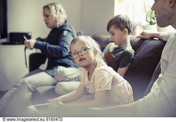 Portrait of handicapped girl sitting with family on sofa at home