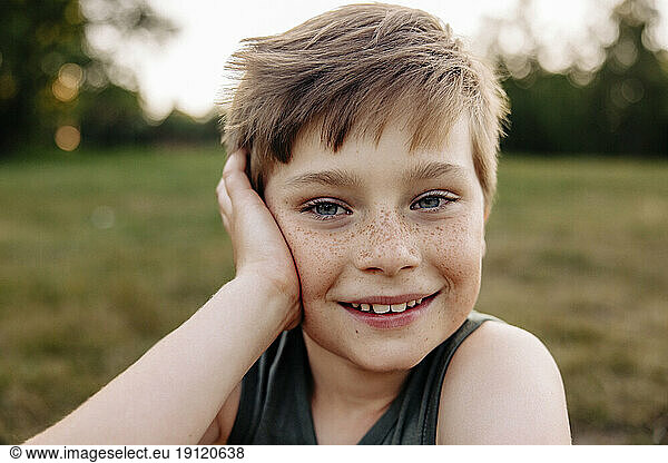 Portrait of happy boy with freckles leaning on elbow