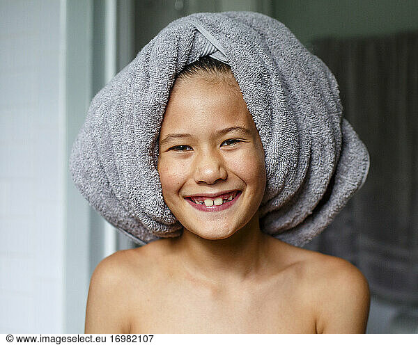 Portrait of happy boy with toothy grin wearing bath towel on his head