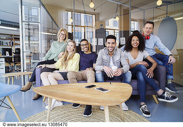 Portrait of happy business people sitting on sofa in office