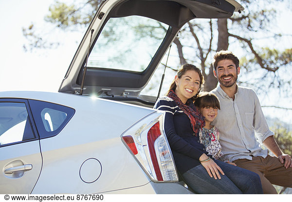 Portrait of happy family at back of car