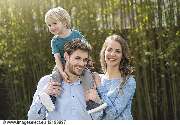 Portrait of happy family in garden in front of bamboo plants