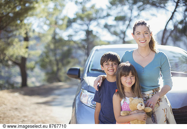 Portrait of happy family leaning on car