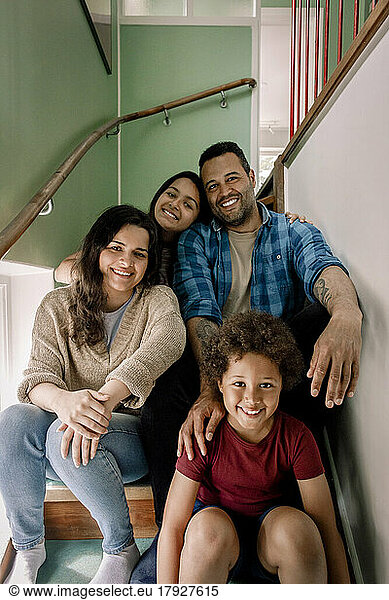 Portrait of happy family sitting together on steps at home