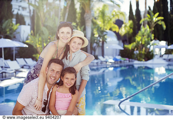 Portrait of happy family with son and daughter by swimming pool