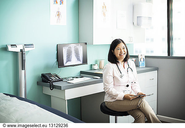 Portrait of happy female doctor sitting in clinic