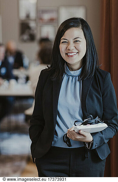 Portrait of happy female entrepreneur with diary in corporate office