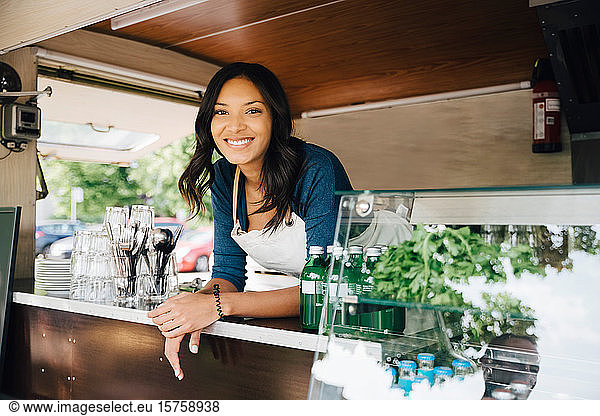 Portrait of happy female owner standing in food truck