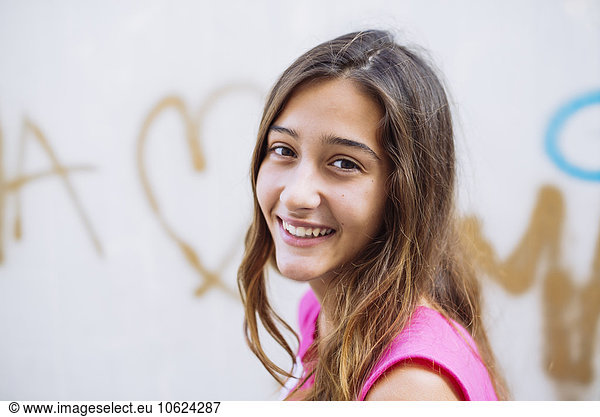 Portrait of happy girl in front of wall with graffiti