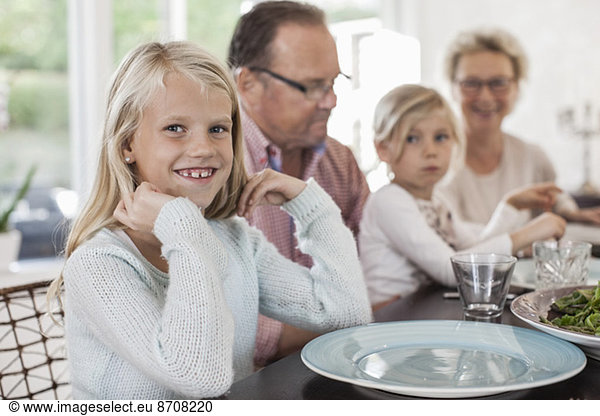Portrait of happy girl sitting with family at dining table