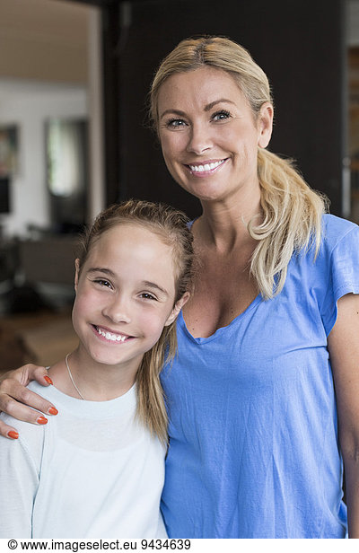 Portrait of happy girl standing with mother standing outside house