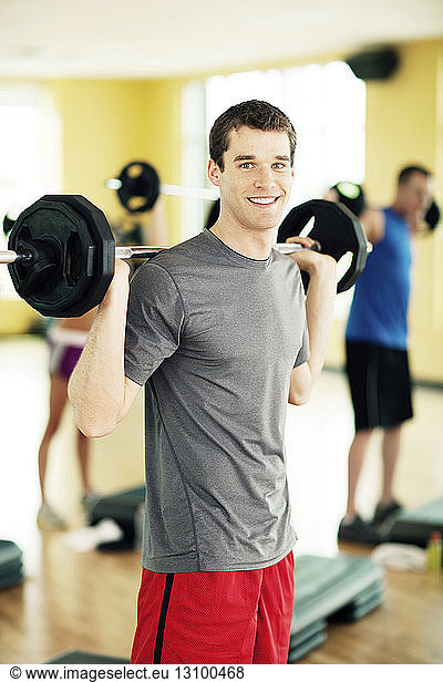 Portrait of happy male athlete lifting barbell in gym