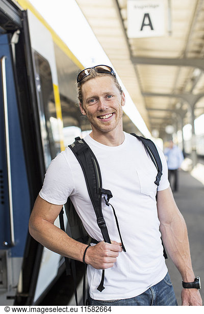 Portrait of happy man standing by metro train at station