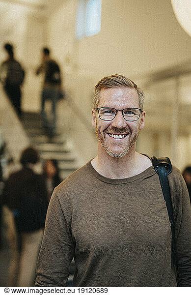 Portrait of happy mature male professor standing in university