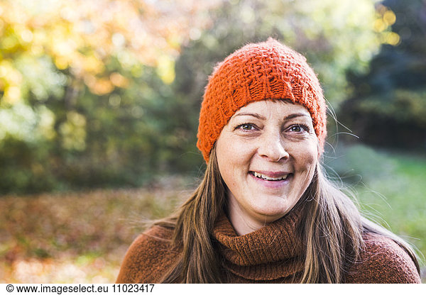 Portrait of happy mature woman wearing knit hat in forest