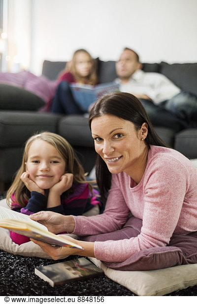 Portrait of happy mother and daughter with story book in living room
