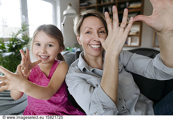 Portrait of happy mother and her little daughter sitting together on the couch having fun