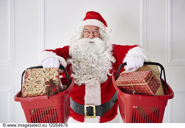 Portrait of happy Santa Claus holding two shopping baskets with Christmas presents