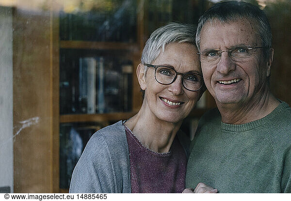 Portrait of happy senior couple behind windowpane