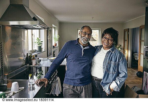 Portrait of happy senior couple standing with each other in kitchen at home