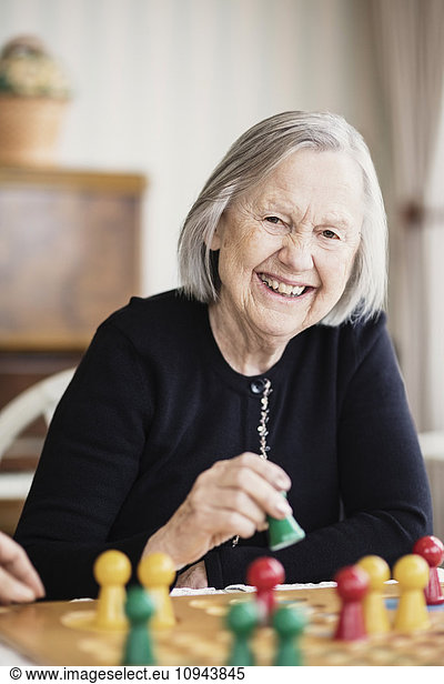 Portrait of happy senior woman playing Ludo in nursing home