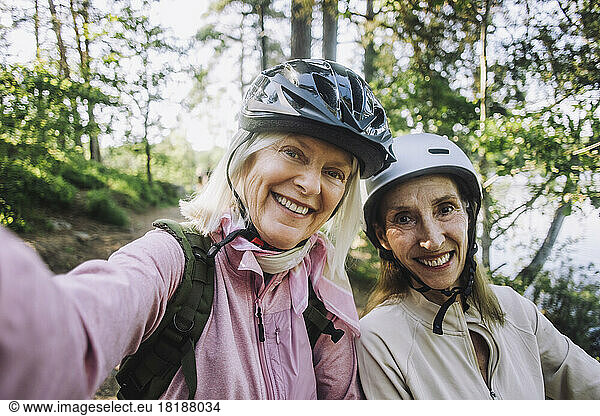 Portrait of happy senior women taking selfie wearing cycling helmet