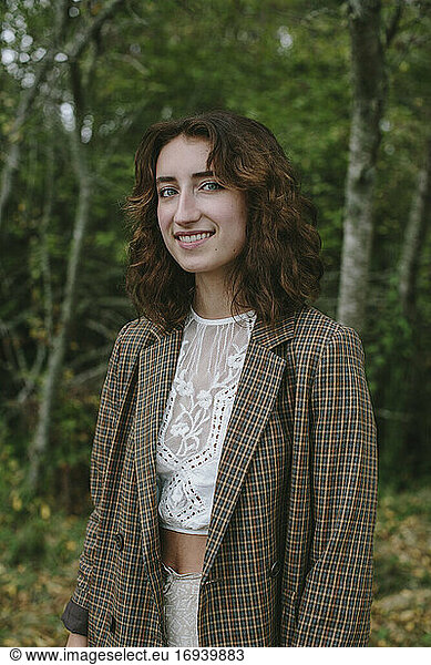 Portrait of happy seventeen year old girl standing in lush forest in Fall  Discovery Park  Seattle  Washington