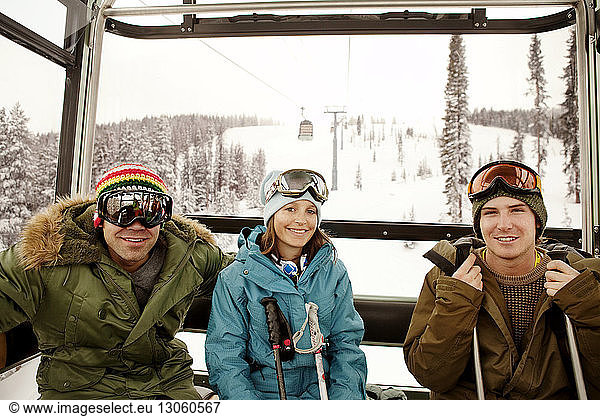 Portrait of happy skiers sitting in overhead cable car