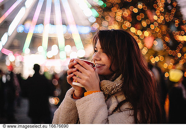 Portrait of happy teenage girl drinking mulled wine during Christmas
