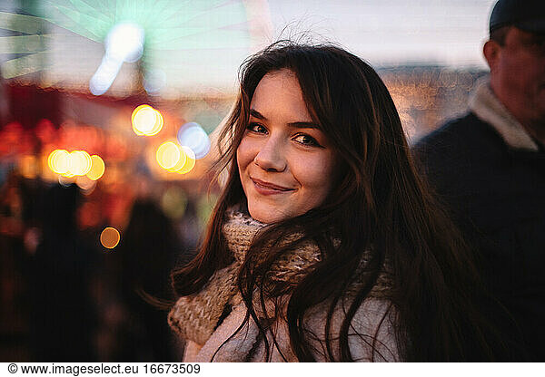 Portrait of happy teenage girl walking in Christmas market in city