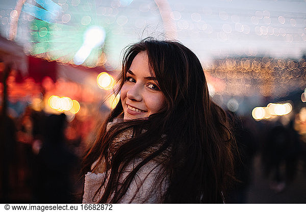 Portrait of happy teenage girl walking in Christmas market in city