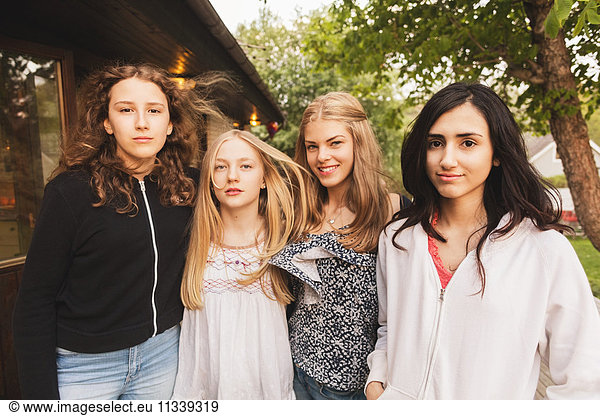Portrait of happy teenage girls standing at yard