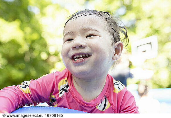 Portrait of Happy Toddler Girl Smiling in Backyard Swimming Pool