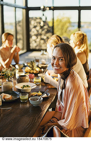 Portrait of happy woman sitting with breakfast on dining table at retreat center