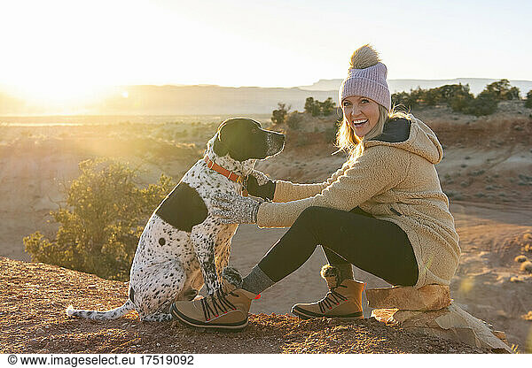 Portrait of happy woman with dog sitting in desert