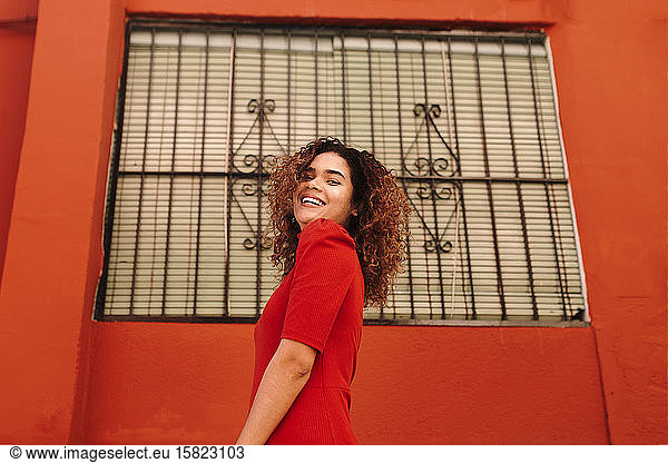 Portrait of happy woman with red dress  dancing in front of a red wall