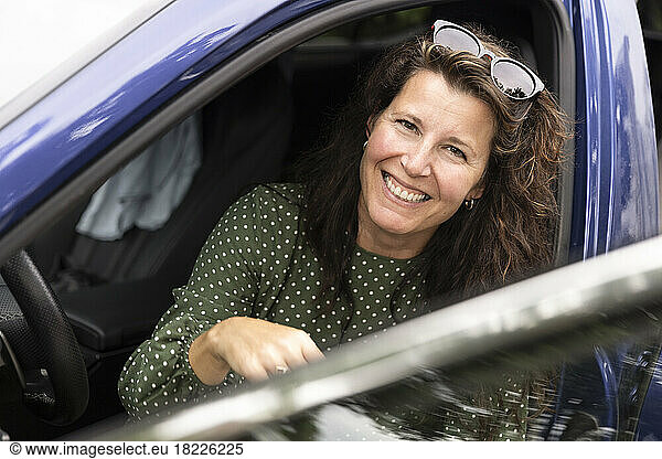 Portrait of happy woman with sunglasses sitting in car