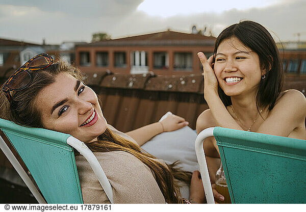 Portrait of happy women sitting on chair at sunset