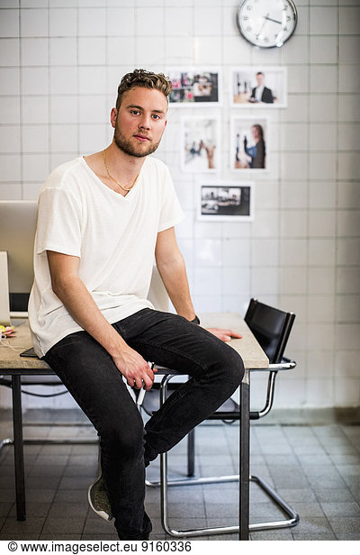 Portrait of happy young businessman using digital tablet in new office