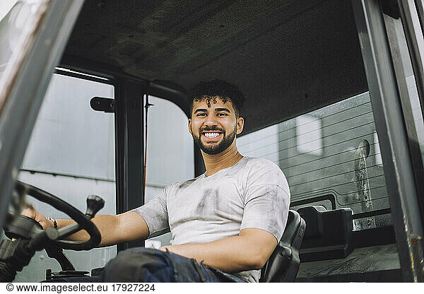 Portrait of happy young construction worker sitting in vehicle