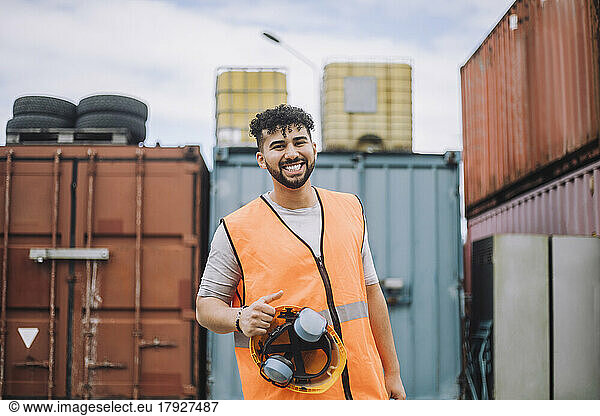 Portrait of happy young construction worker with hardhat at site